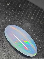 Oblique view of oval cabochon showing translucent body and multicolour play-of-color