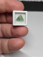Front view of triangular blue-green sapphire in display box