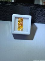 Row of square yellow-orange sapphires in display box