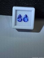 Pair of pear cut violet-blue tanzanites in white gem box