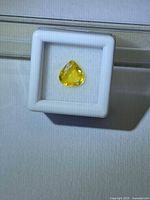 Pear-shaped yellow sapphire in white gemstone box, frontal view