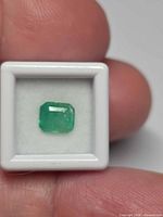 Front view of emerald in display box showing color and cut