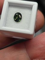 Oval tri-colored sapphire in display box, showing face-up color