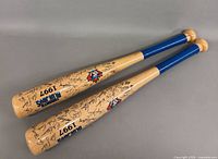 Two souvenir bats showing logo, year and printed signatures