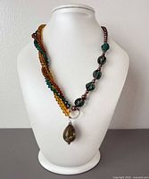 Necklace displayed on bust showing multistrand crystals, green beads, pearls and gemstone pendant
