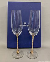 Two Swarovski Crystalline flutes standing before blue box