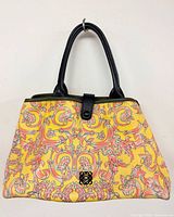 Front view of yellow floral Loewe tote with black handles and logo