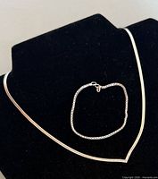 Necklace on display form with bracelet laid inside