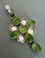 Front view of silver pendant with seven peridot cabochons