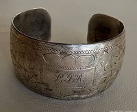 Front view showing engraved floral pattern and monogram cartouche
