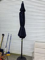 Full view closed navy umbrella on stand
