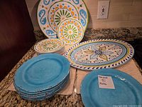 Stacks of turquoise plates, medallion plates, and oval platter displayed on countertop