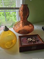 Group view showing amber glass vase, yellow glass vessel, wooden jewelry box