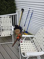 Two folding chairs with webbing, garden tools grouped