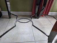 Underside showing black metal legs and circular stretcher
