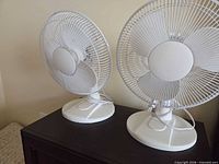 Front view showing both matching white table fans on a surface