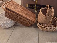 Group of four visible baskets including rectangular lidded, tall round, shallow oval, and white-washed round