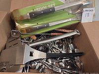 Overview of box contents including packaged grill tool set and loose utensils