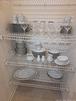 Full shelving view showing china stacks, cups, saucers, goblets, serving pieces
