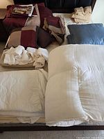 Full lot on bed showing comforters, topper, sheets, pillows