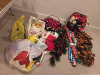 Overall view of lot on floor showing plastic bags, wreath, garland, wrapping paper, floral basket and autumn leaves