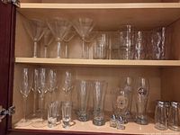 Two cabinet shelves with entire assortment of glassware visible