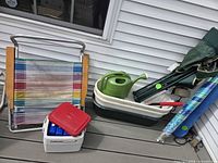 Group shot showing striped chair, Coleman cooler, watering can, nested basins, folded camp chair and brush