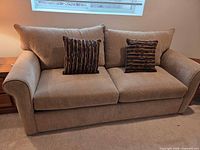 Front view of taupe sofa bed with two patterned pillows
