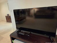 Front view of Samsung 42" TV on stand with remote and HDMI cable