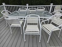 Overall view of glass-top table with surrounding white strap chairs