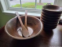 large wooden serving bowl with utensils and stacked smaller bowls