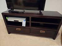 Front view of dark brown wooden TV stand showing shelves, drawers, and pulls
