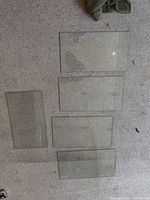 Five rectangular tempered glass shelves on carpet