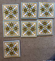Group of seven matching ceramic tiles displayed on floor