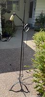 Full view of wrought iron floor lamp showing adjustable arm and tripod base