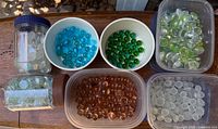 Grouped containers showing assorted colored glass marbles and flat pebbles