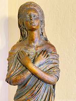 Close-up of statue upper body and face showing antique bronze finish and crossed arms