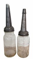 Both antique glass oil bottles side by side with metal spouts attached