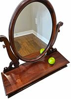 Front view showing oval mirror, wood supports, apples for scale