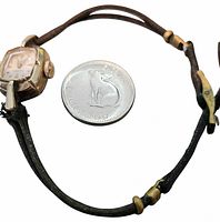 Front view of watch beside Canadian quarter for scale