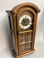 Full front view of Hermle wooden wall clock showing entire case and pendulum