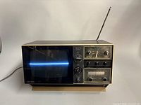 Front view showing TV screen, radio dial, clock, controls, antenna