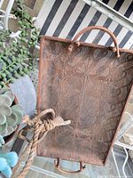 Overhead view of pierced metal tray, partial view of hanging planter, rope hanger, faux succulents