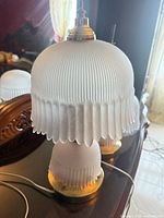 Full view of one lamp showing frosted ribbed glass shade and brass base