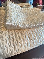Folded ivory satin quilted bedspread with matching sham on top