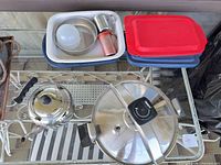 Entire lot on glass shelf showing pressure cooker, tea kettle, CorningWare dish, plastic containers and small metal items