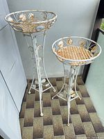 Full view of both white wrought iron plant stands, showing height difference