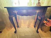 Front view of Queen Anne style console table with tassel pulls and cabriole legs