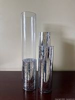 Tall clear glass vase beside two mercury-glass vases demonstrating size and finish