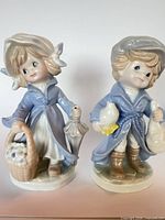 Front view of both porcelain child figurines standing side by side